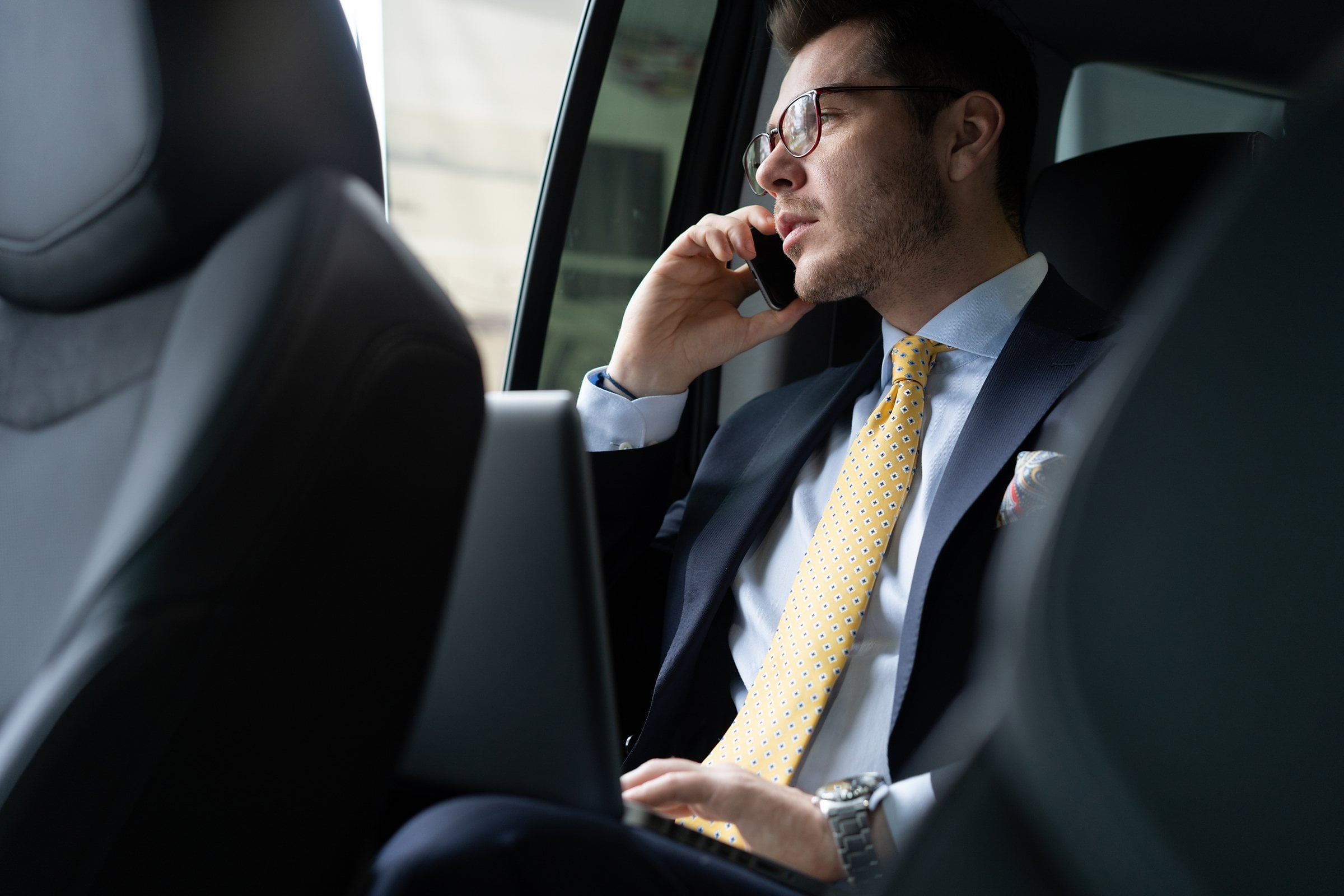 Business traveler taking a phone call in the back seat of a chauffeured car