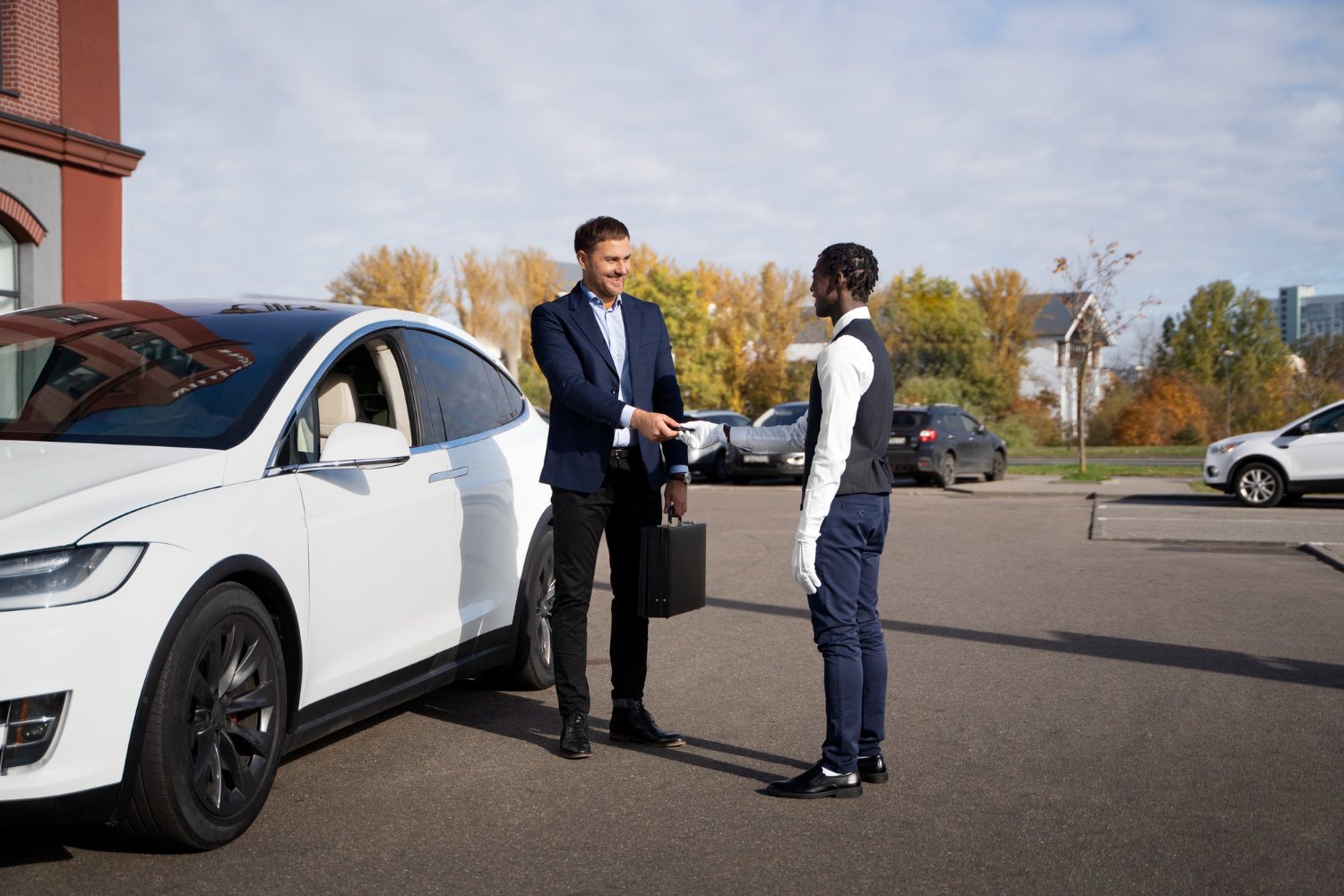Chauffeur shaking hands with a business traveler beside a white car