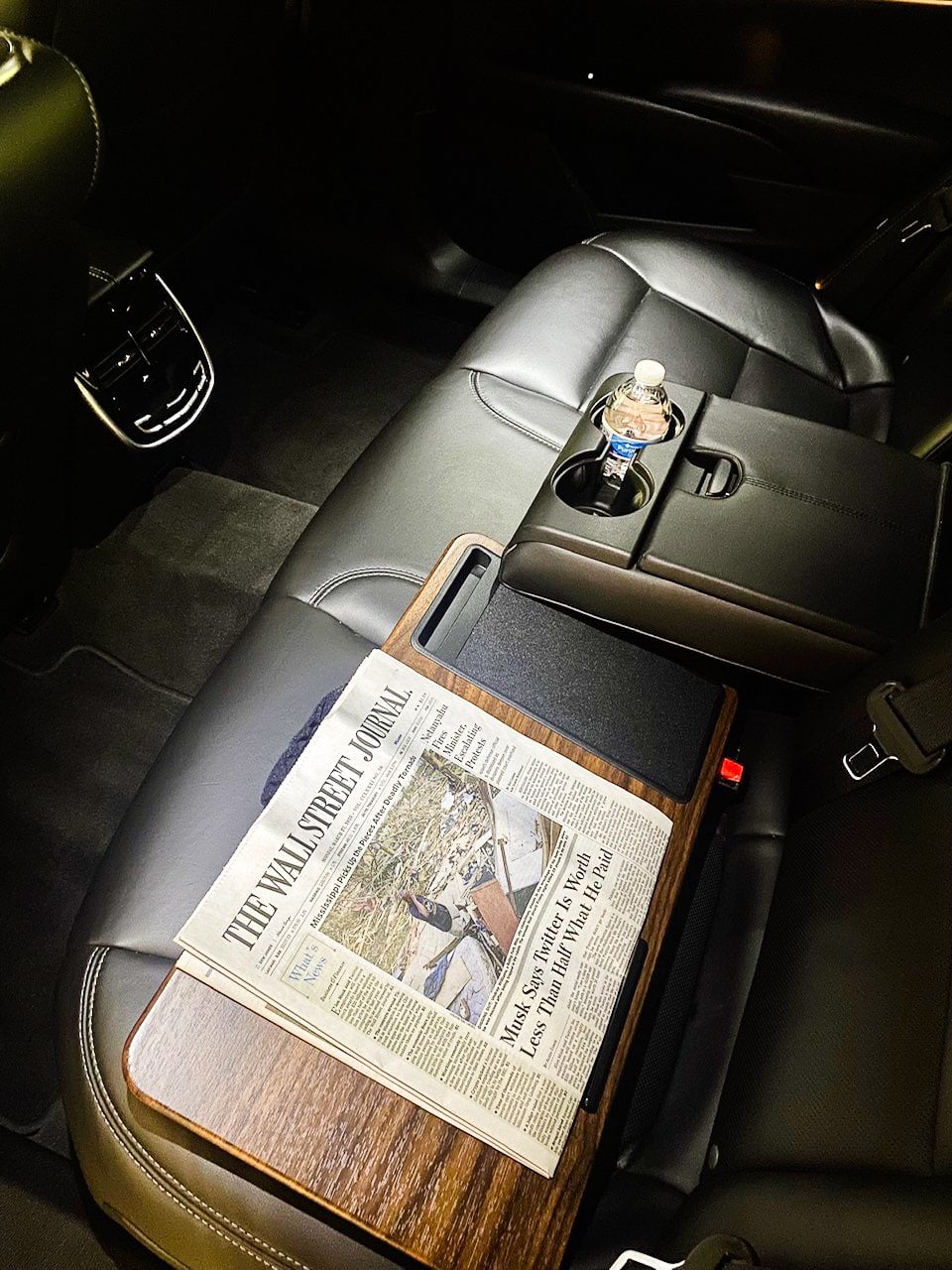 Rear seat of a chauffeured vehicle with a newspaper on the armrest