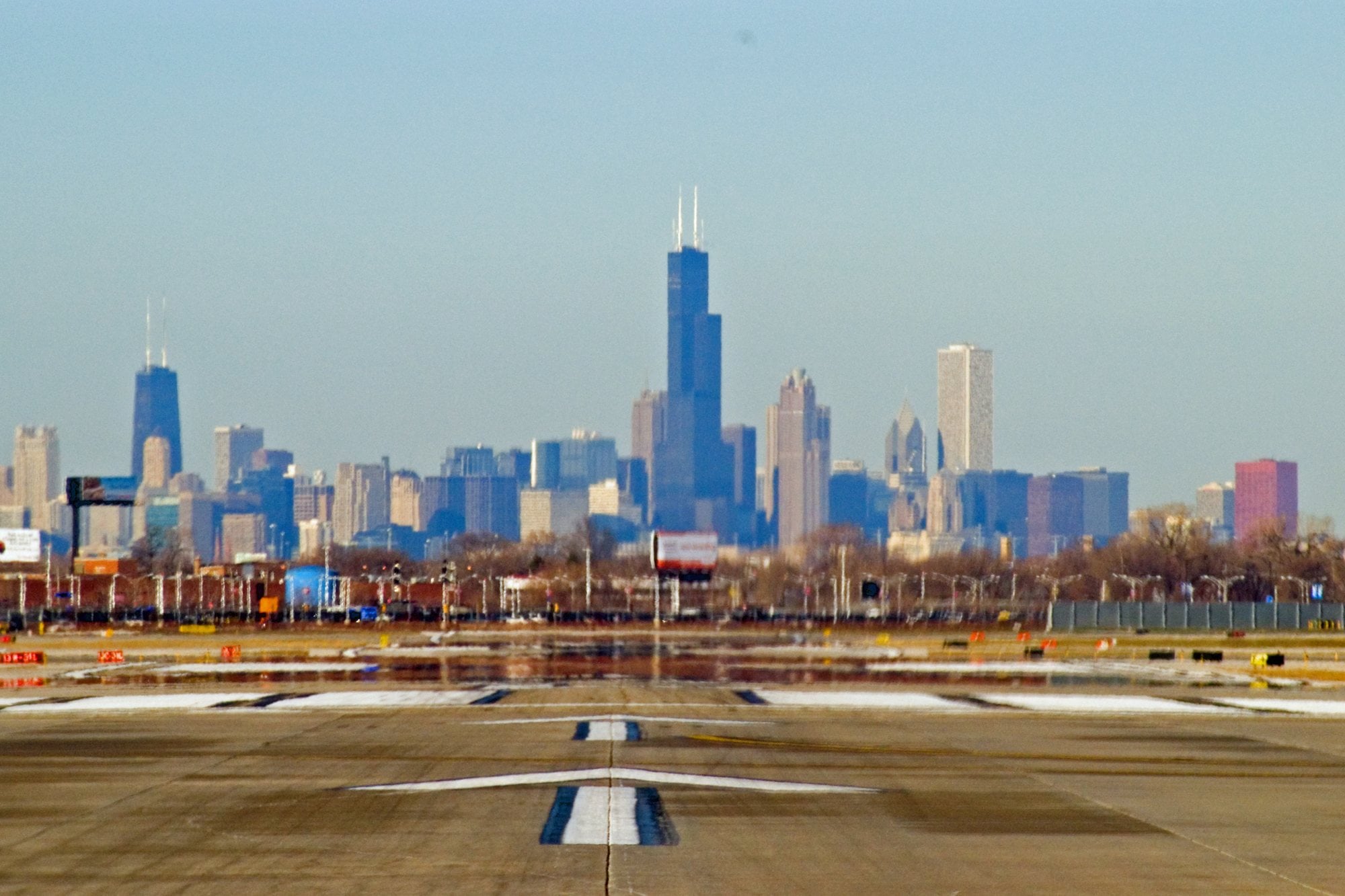 The downtown Chicago skyline on the horizon beyond a runway at Midway International Airport