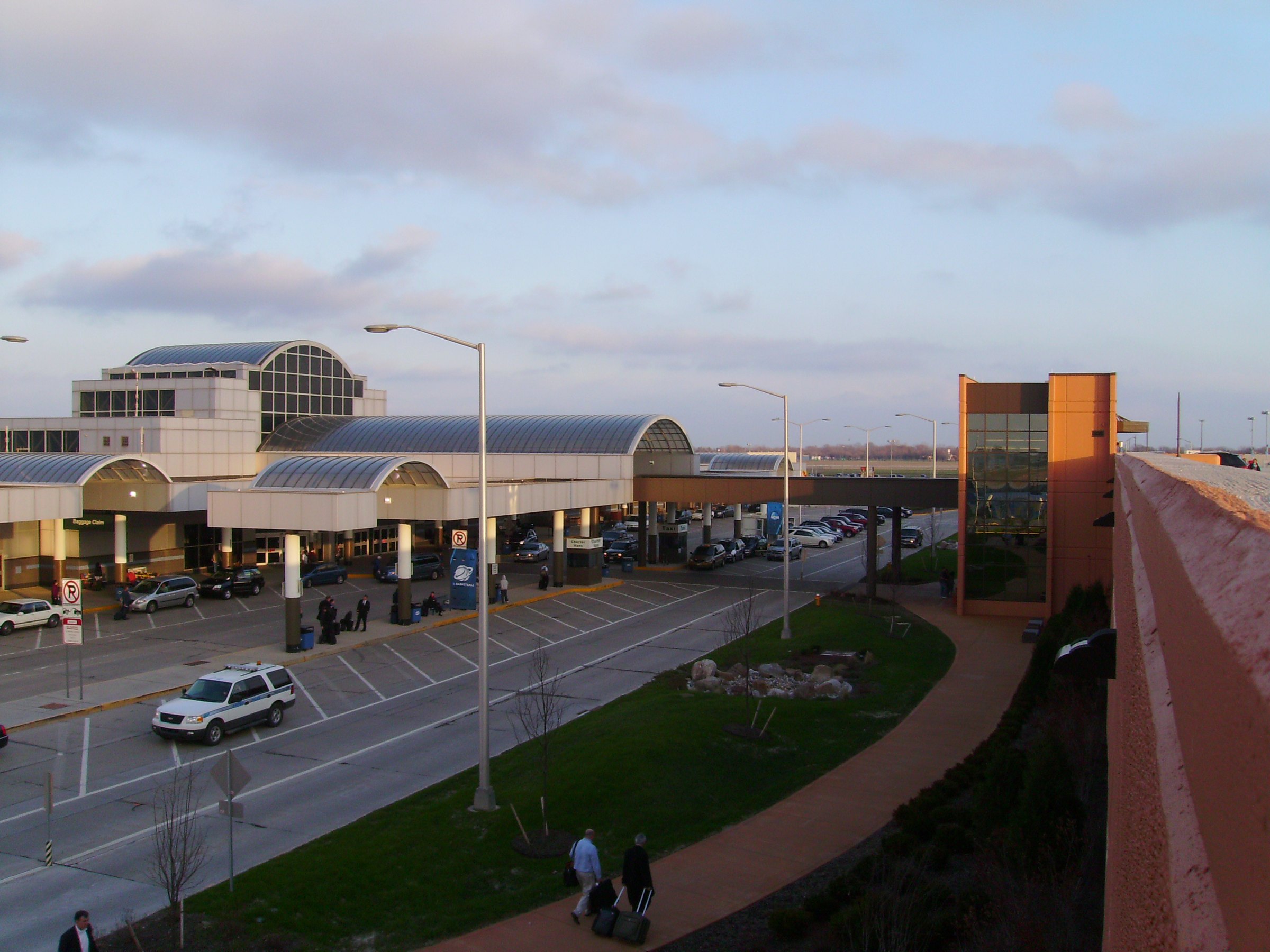 Travelers and cars on the terminal roadway at Dayton International Airport in Ohio at dusk