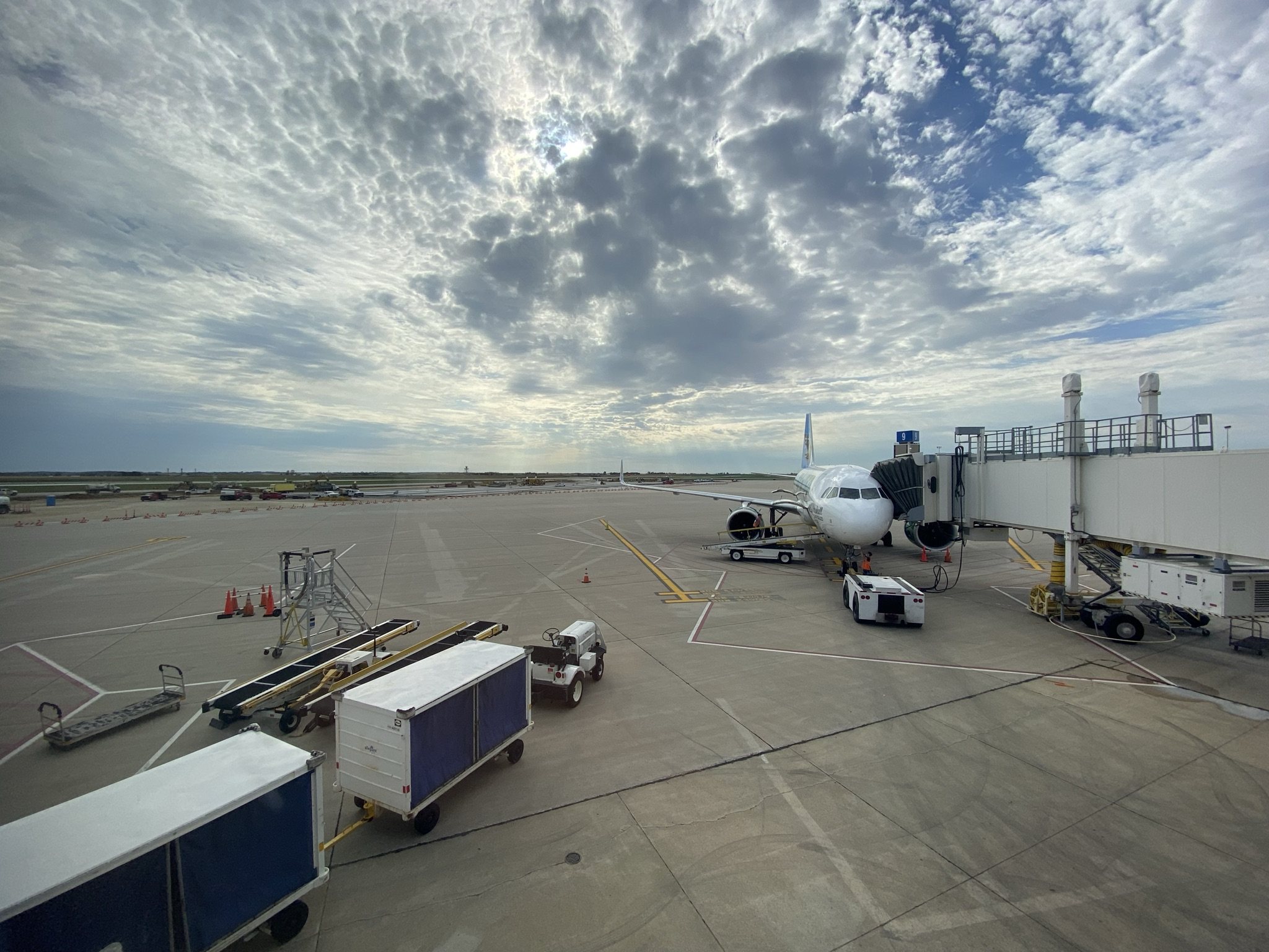 An airliner at the jet bridge on the ramp at The Eastern Iowa Airport in Cedar Rapids under a broken sky