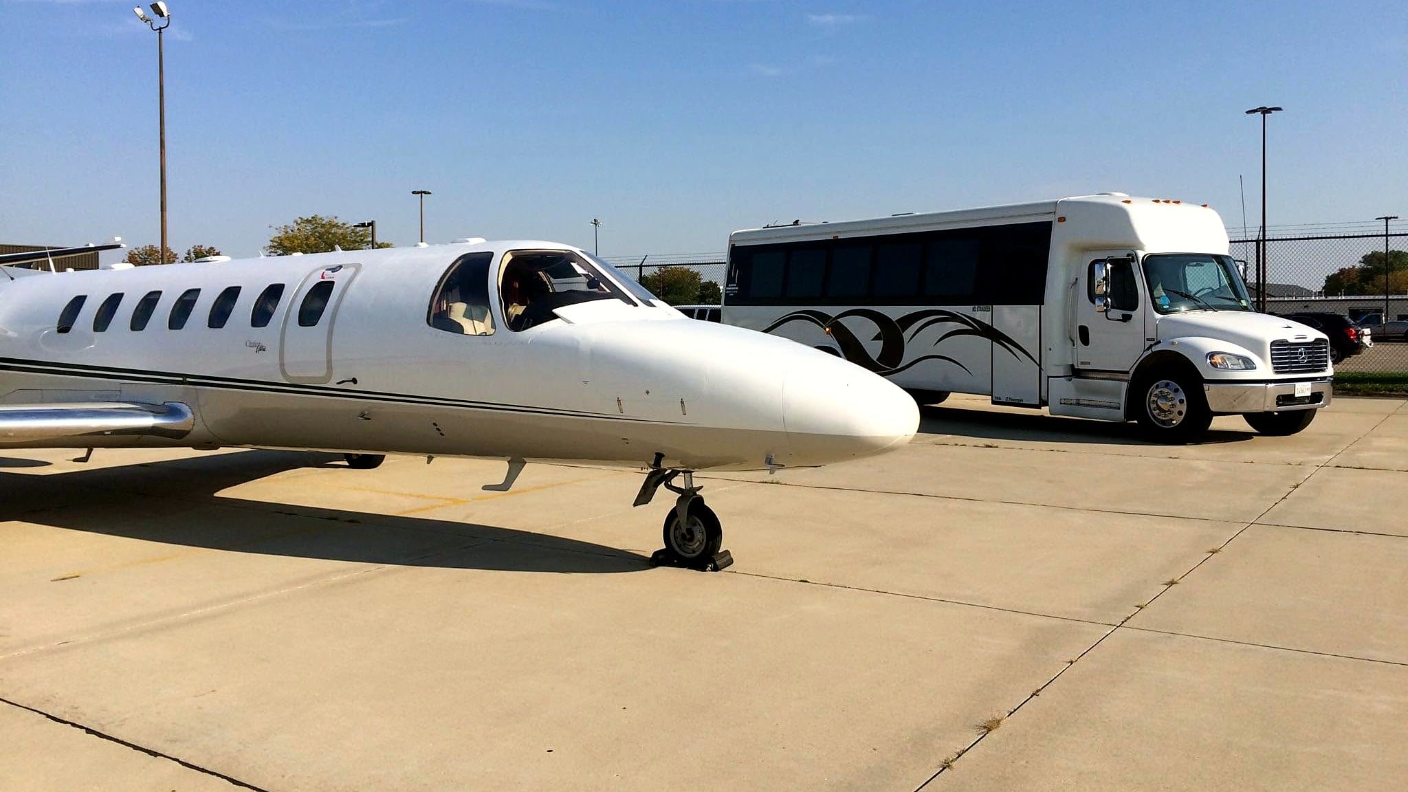 Executive Transportation shuttle coach parked beside a private jet on the ramp