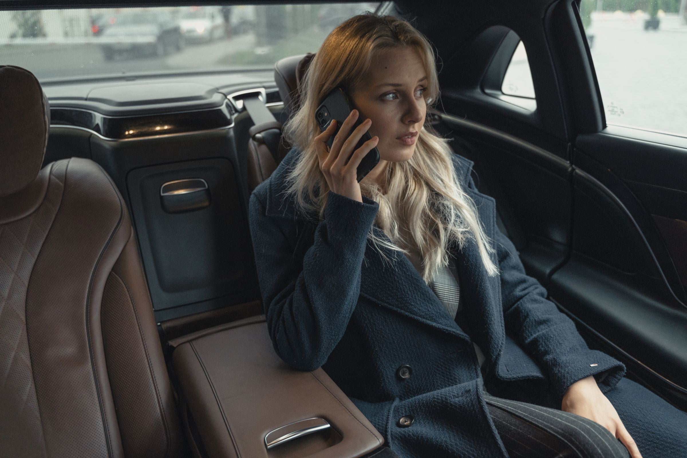 Traveler taking a phone call from the rear seat of a chauffeured black sedan