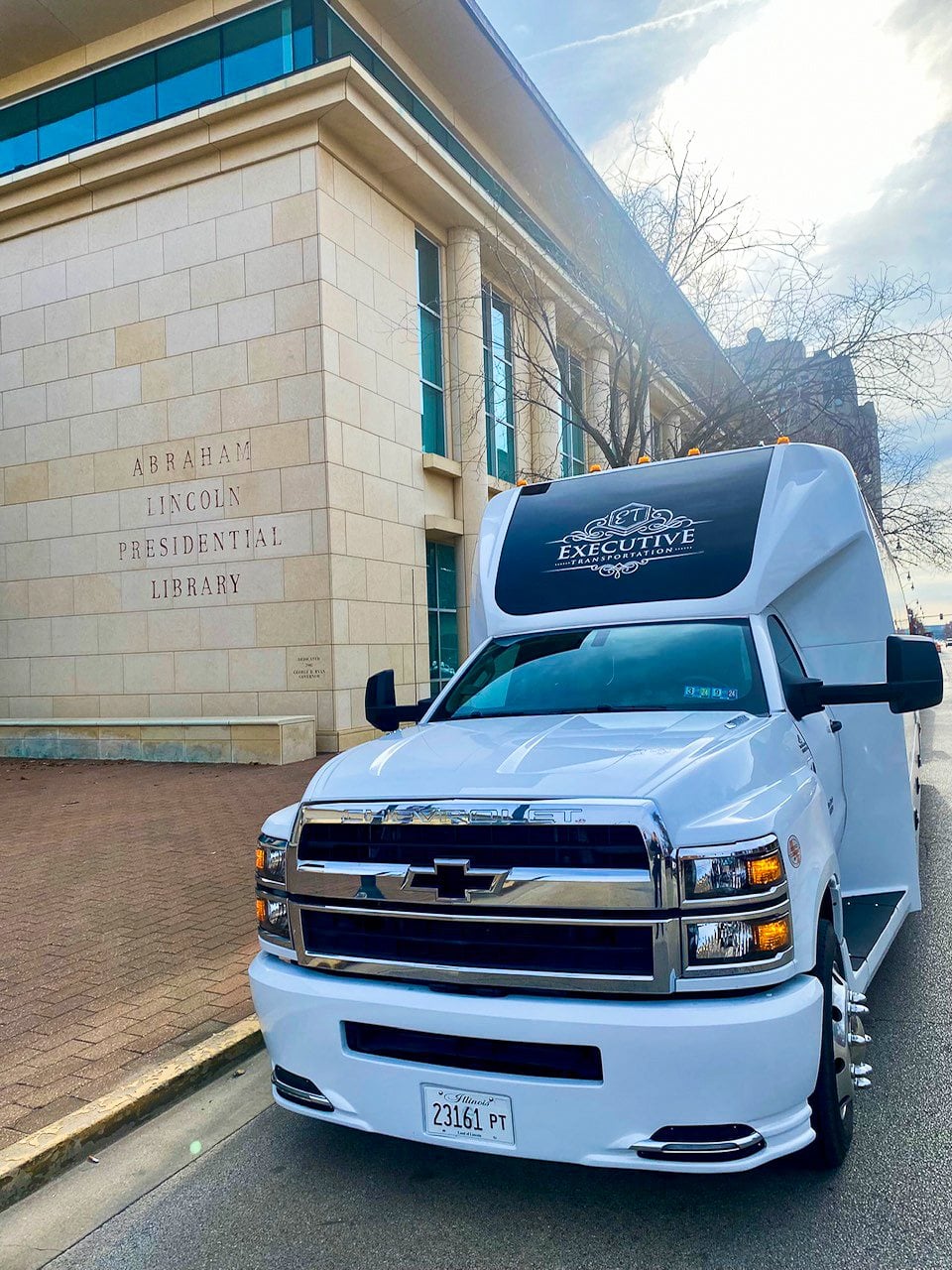 White Executive Transportation shuttle bus parked outside a downtown building