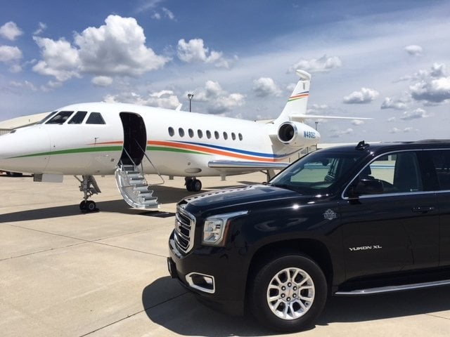 Black GMC Yukon XL beside a private jet on the tarmac