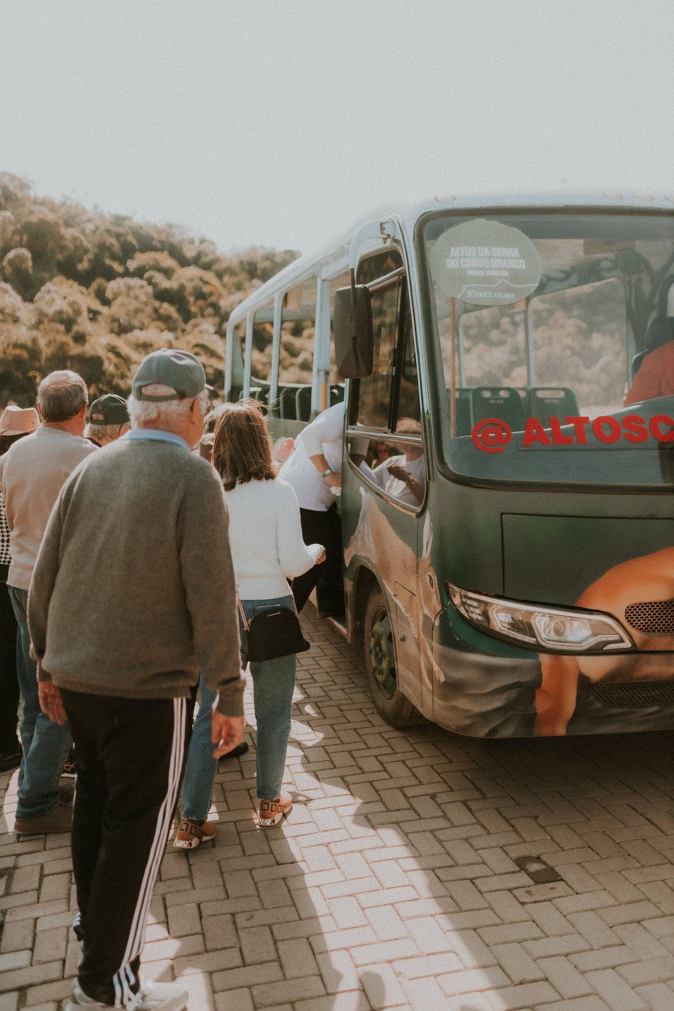A group of travelers with bags walks toward a parked coach bus to board.