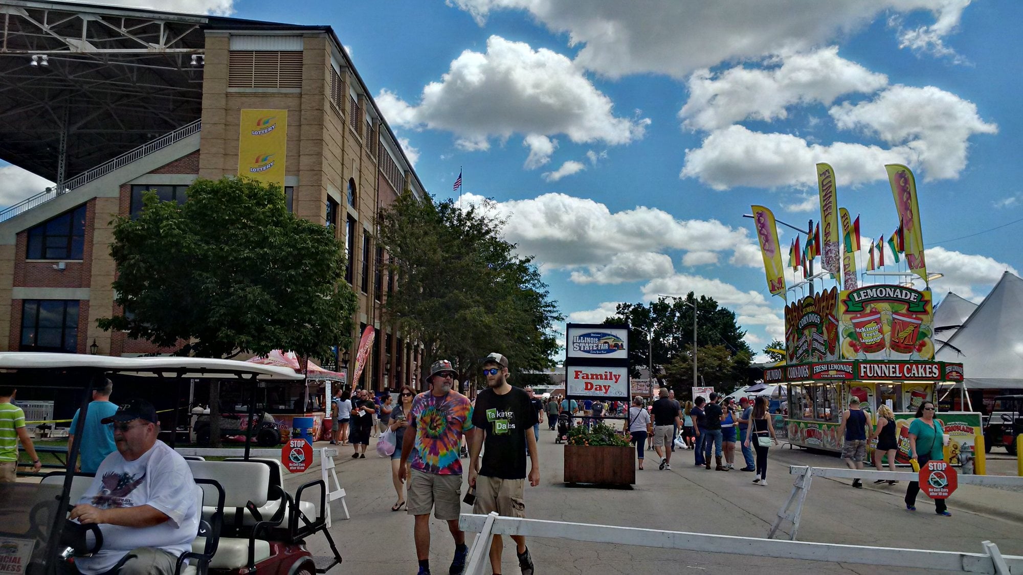 Fairgoers walk along Grandstand Avenue past the grandstand and food stands at the Illinois State Fair.