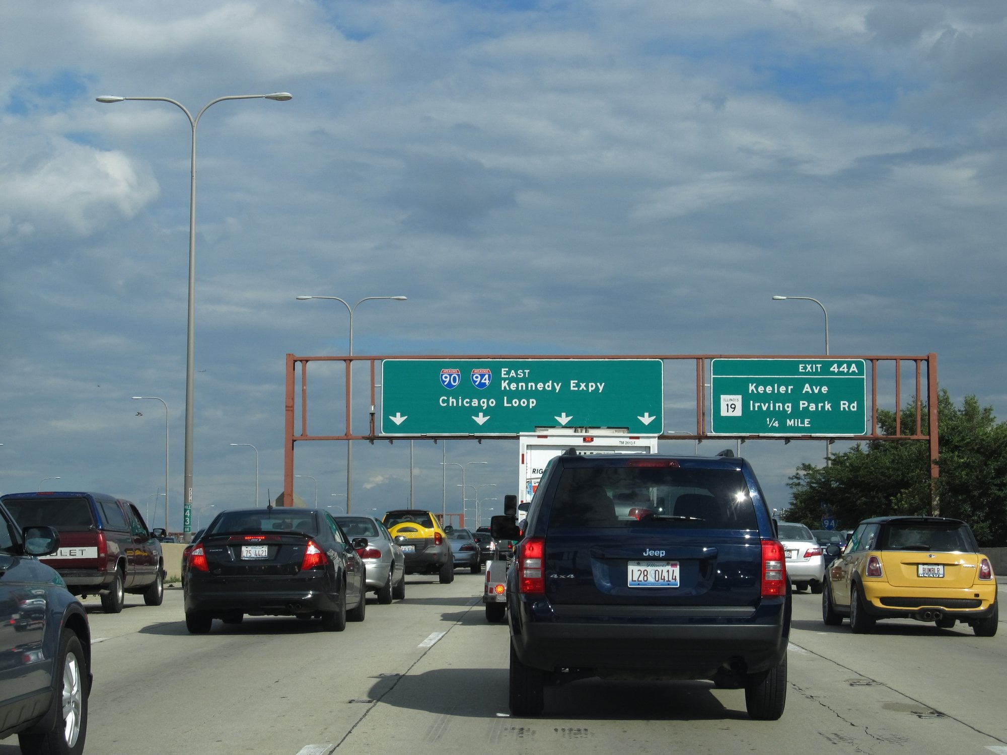 Lanes of slow traffic on the Kennedy Expressway in Chicago beneath green overhead highway signs
