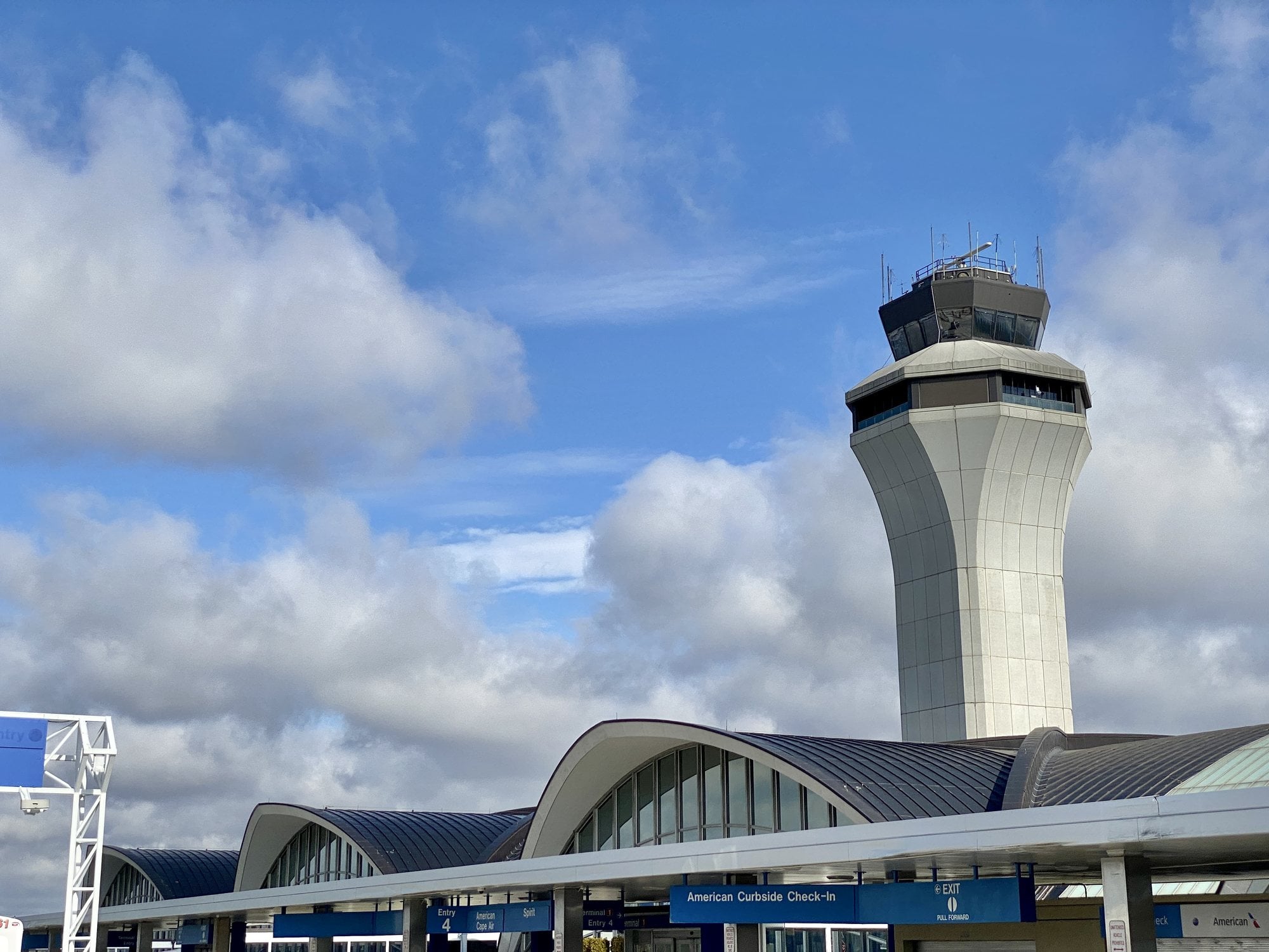 The vaulted concrete shells and control tower of Terminal 1 at St. Louis Lambert International Airport under a blue sky