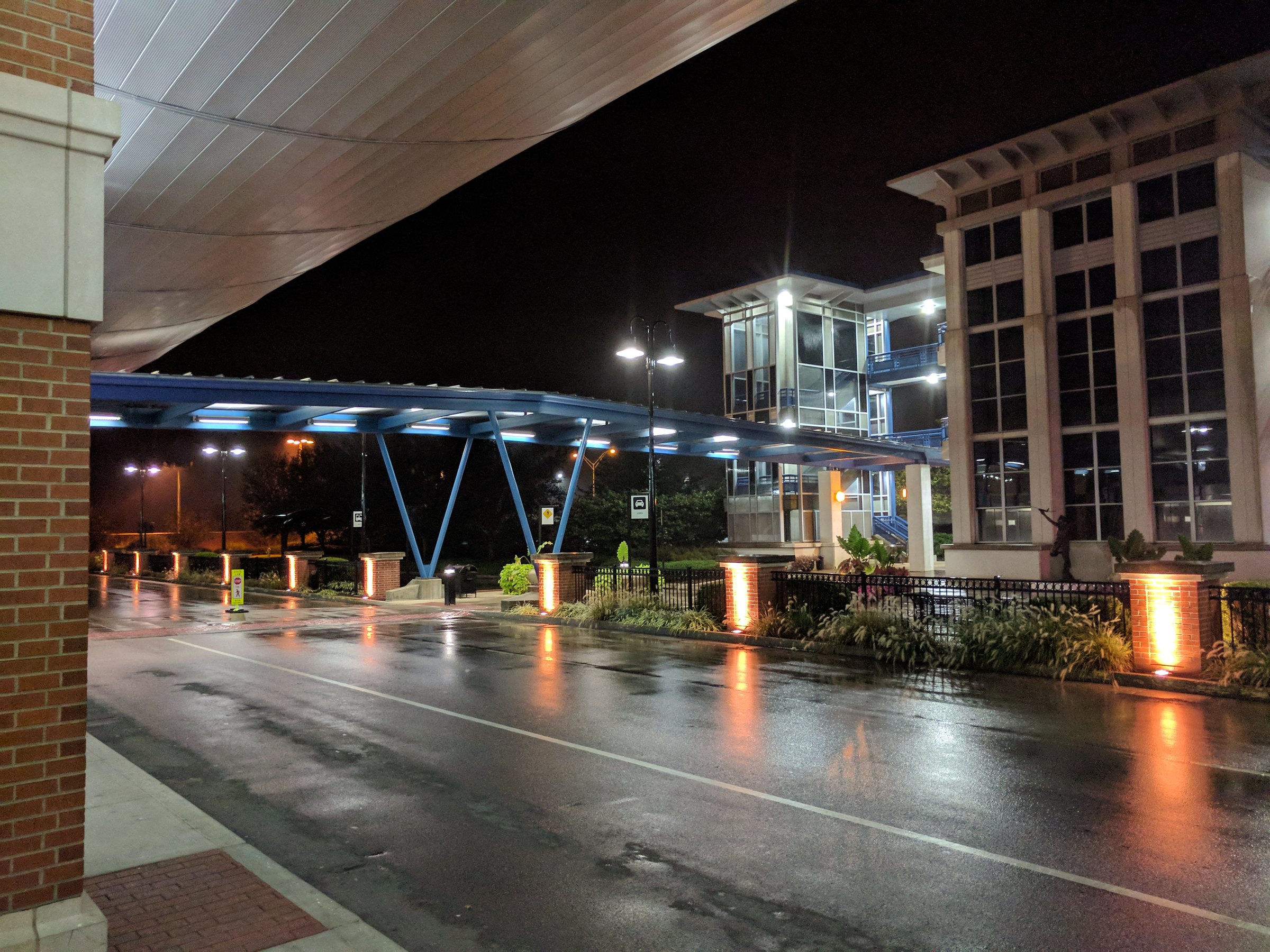The lit terminal canopy and wet roadway outside Blue Grass Airport in Lexington, Kentucky, at night