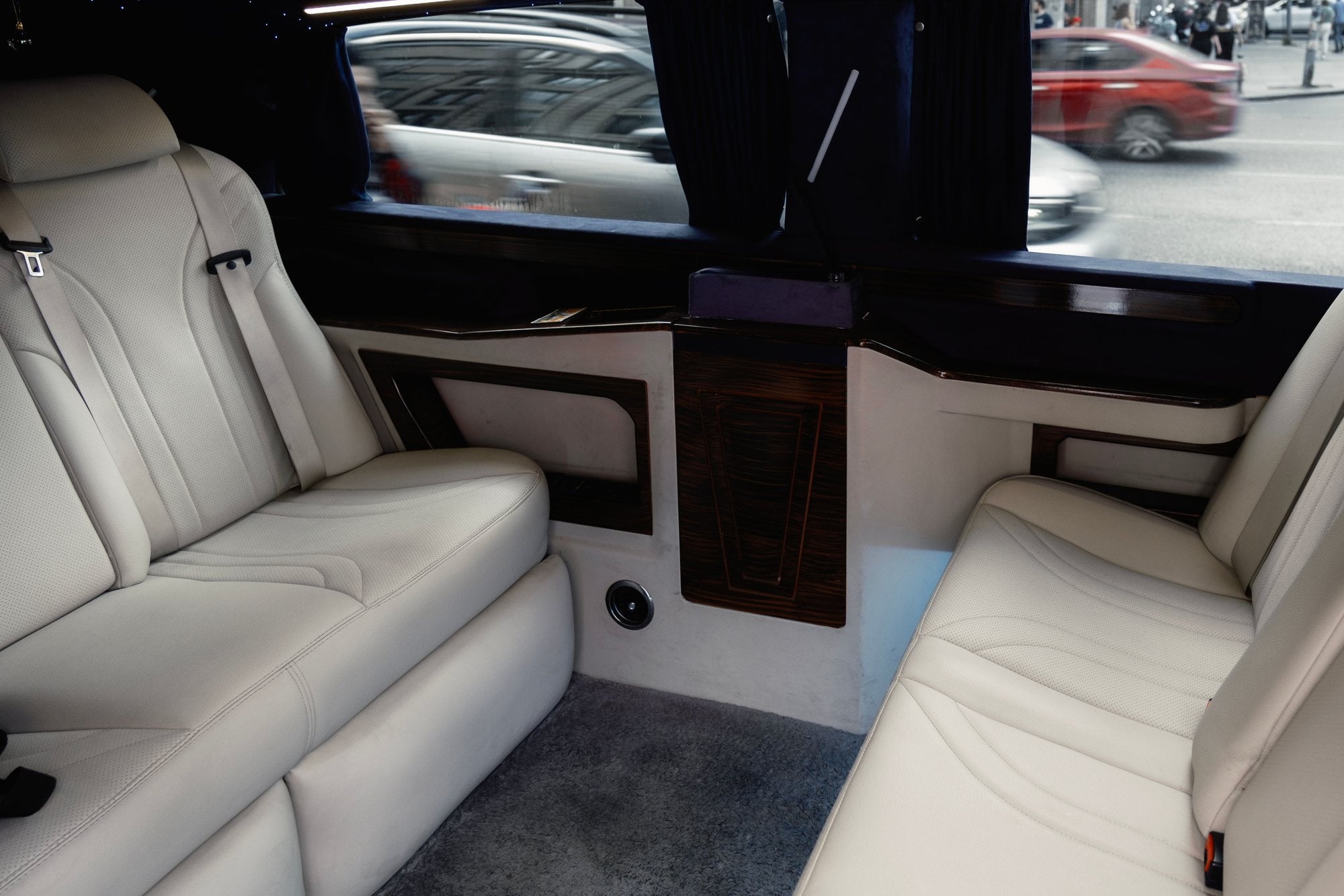 White leather bench seats line the passenger cabin of a limousine.