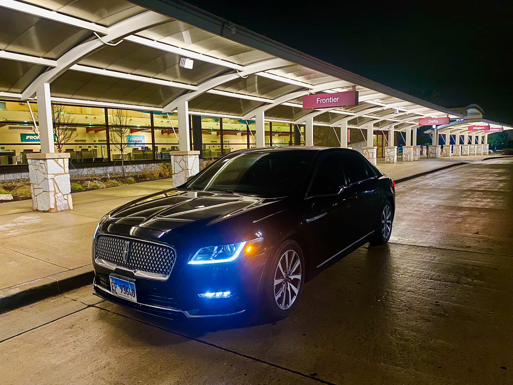 Black Lincoln Continental sedan waiting outside an airport terminal