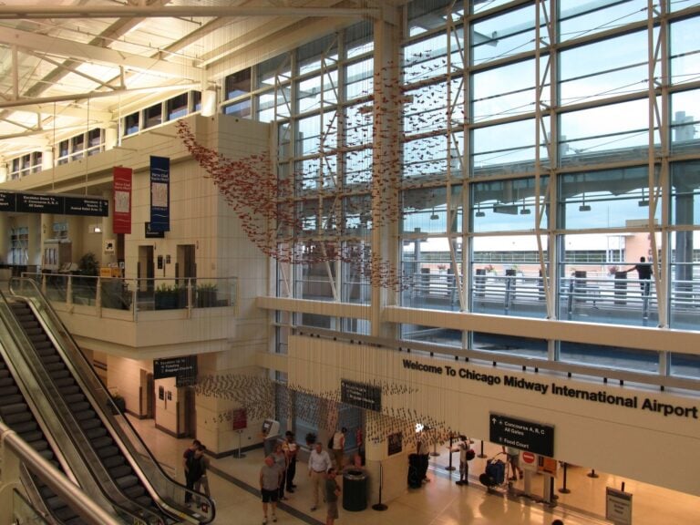 The bright ticketing hall at Chicago Midway International Airport with escalators and a welcome sign