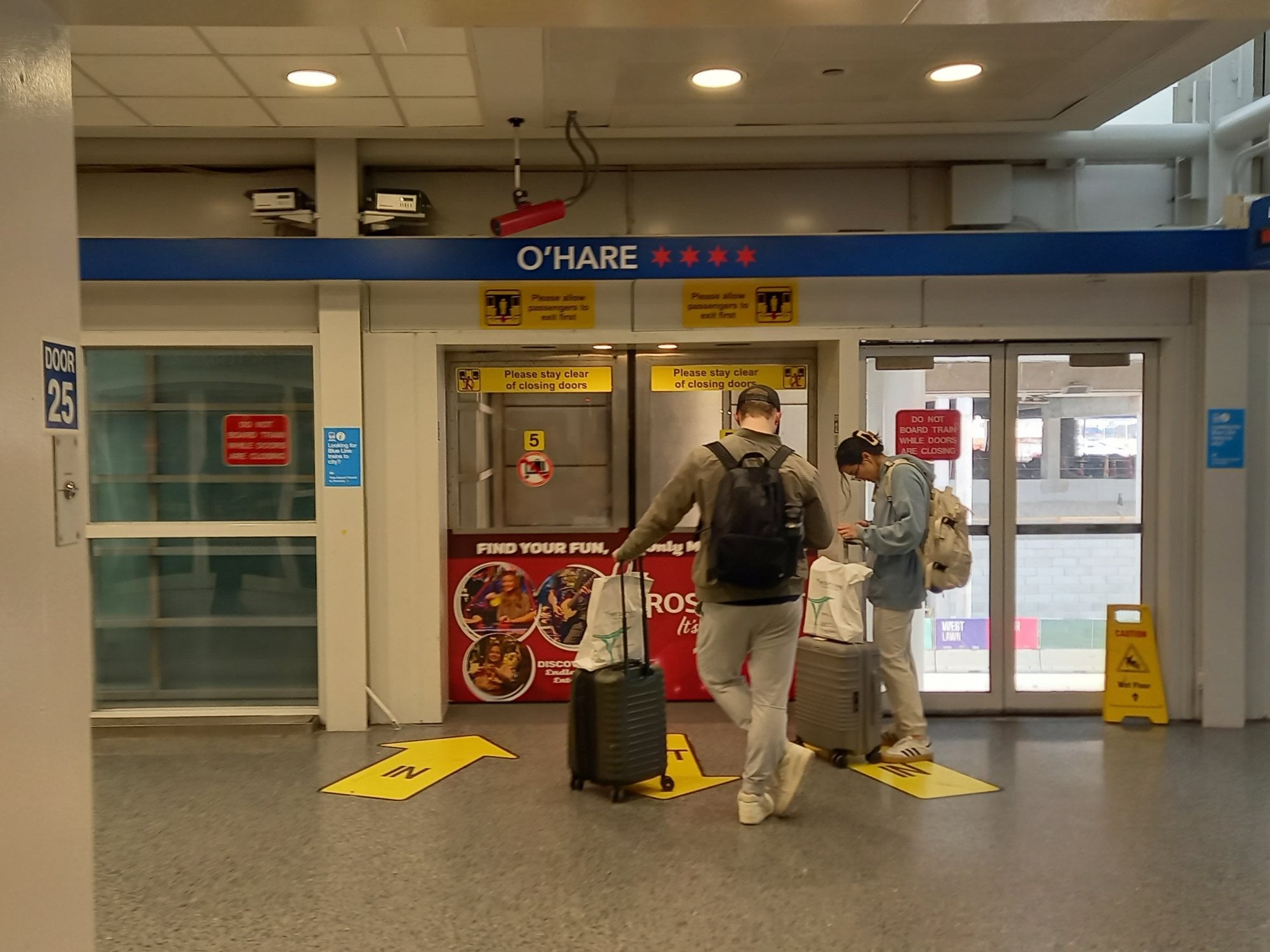 Travelers with rolling luggage entering the Airport Transit System station at O'Hare Terminal 5