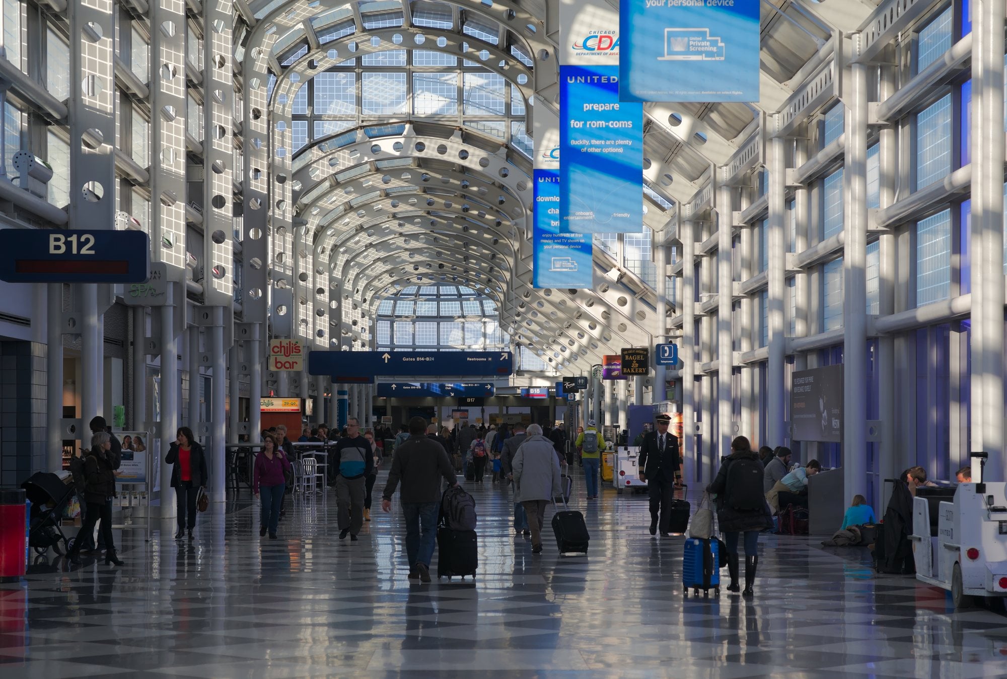 Travelers walk through the arched glass ceiling of Concourse B at Chicago O'Hare International Airport.