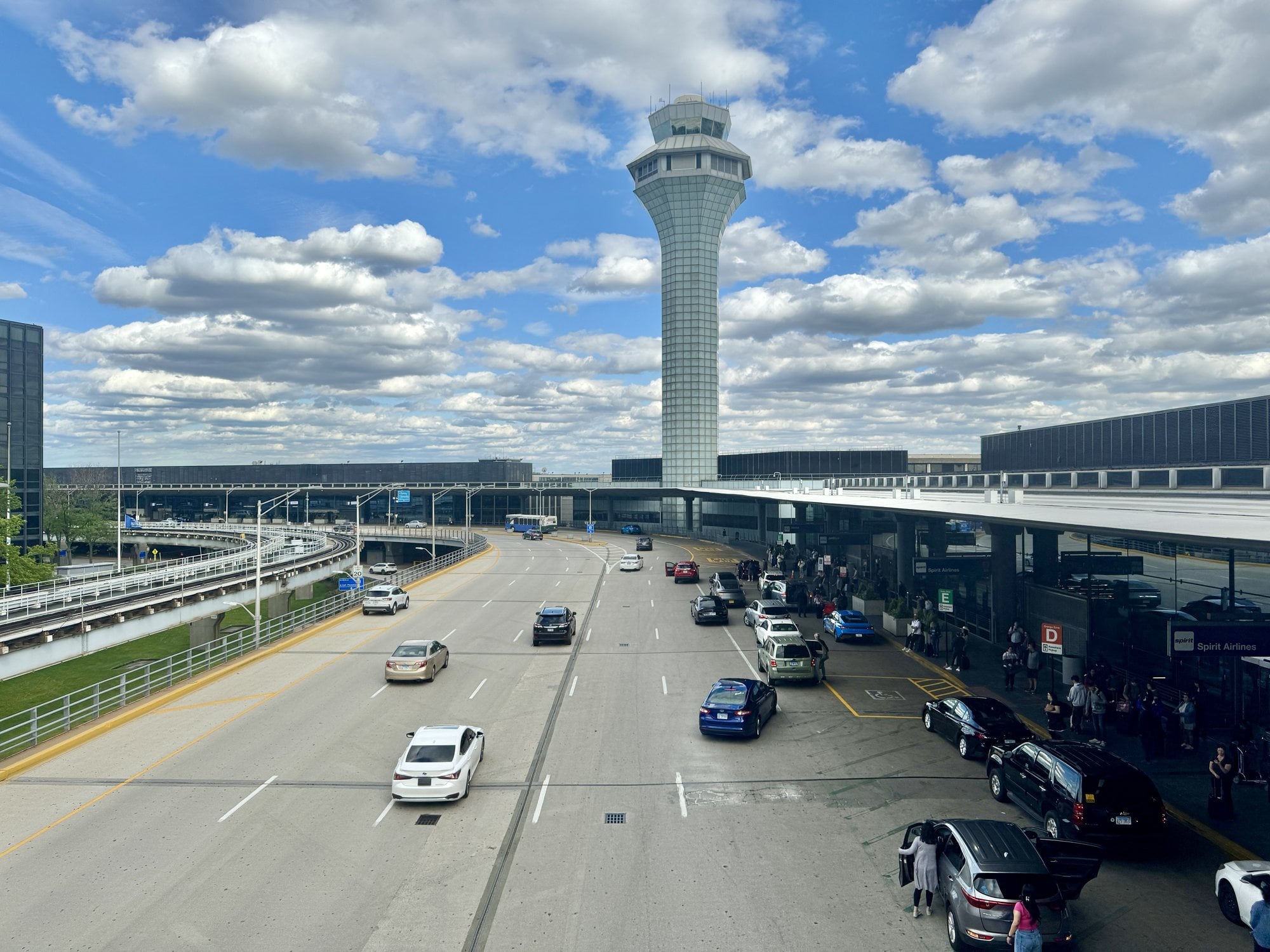 Cars and taxis on the upper-level roadway in front of Terminals 2 and 3 at Chicago O'Hare International Airport, beneath the control tower