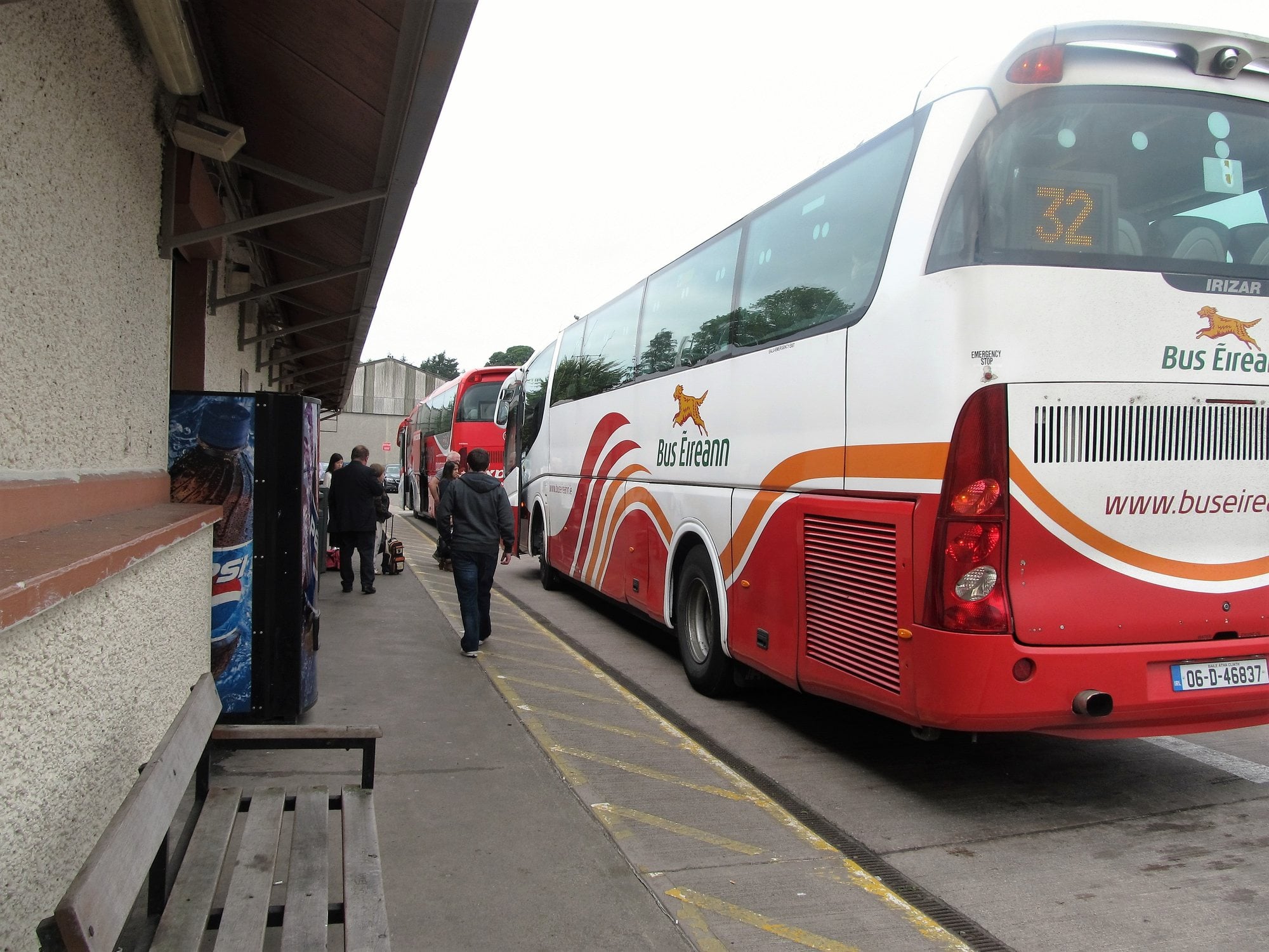 A group of passengers lines up to board intercity coaches at a bus station.