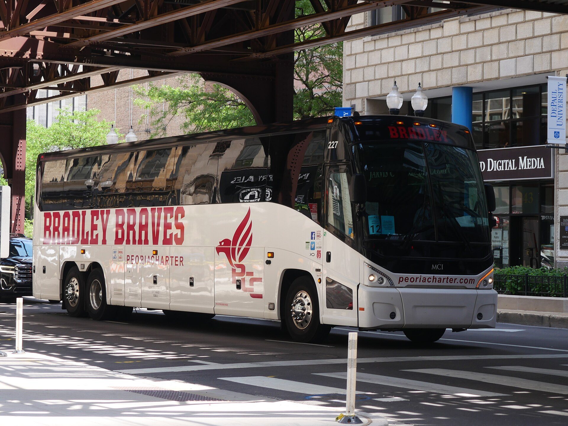 A Peoria Charter intercity motorcoach on a Chicago street beneath the elevated train tracks.