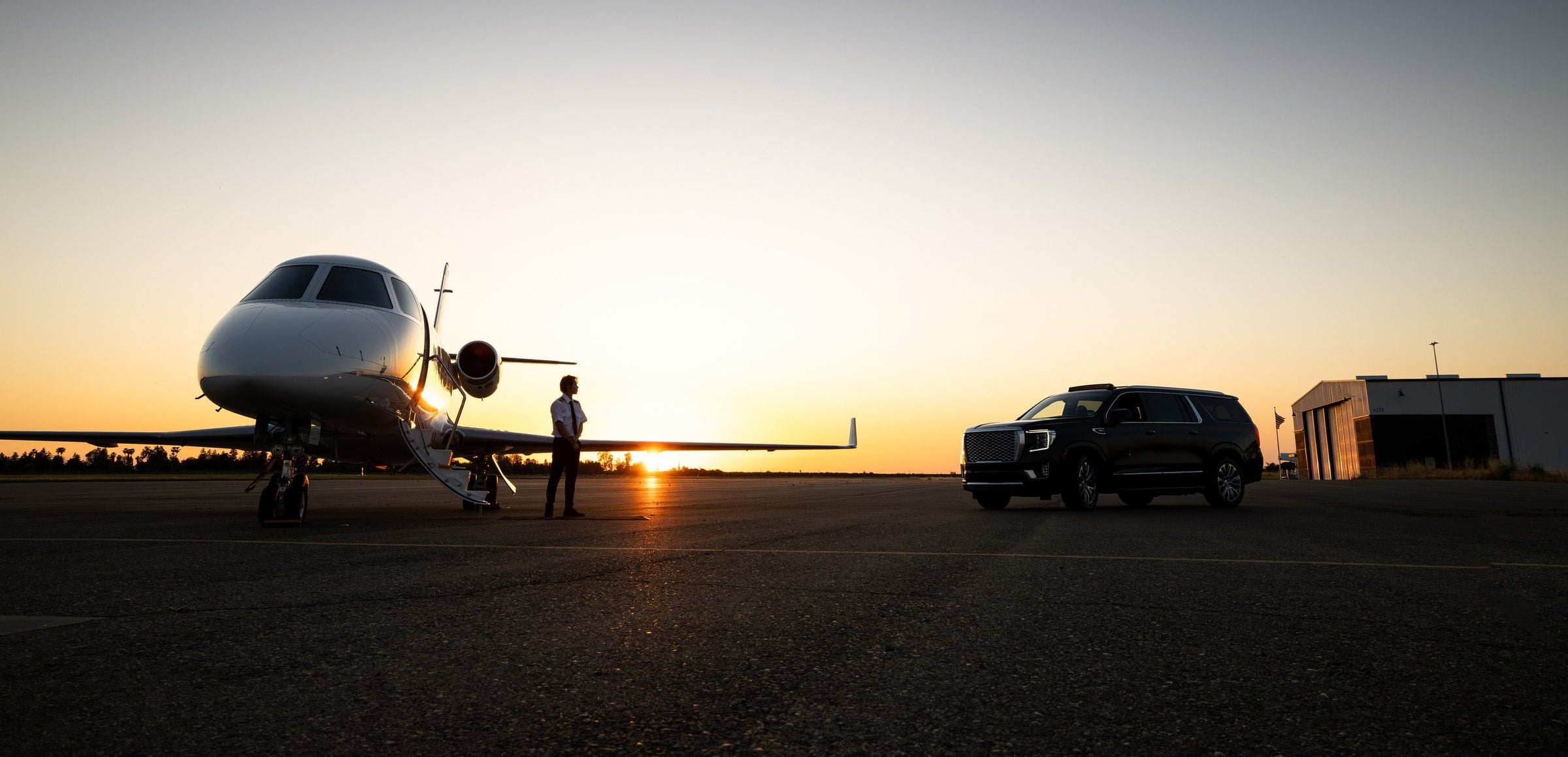Private jet and a black SUV on a tarmac at sunset before a chauffeured transfer