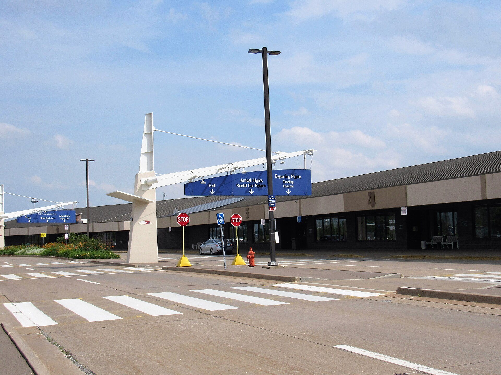 The terminal roadway at Quad Cities International Airport in Moline, Illinois, with overhead signs for departing flights, arrival flights and rental car return
