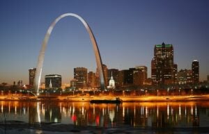 The Gateway Arch and the St. Louis skyline lit at night above the Mississippi River.