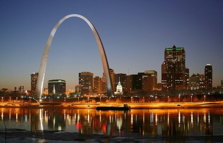 The Gateway Arch and the St. Louis skyline lit at night above the Mississippi River.
