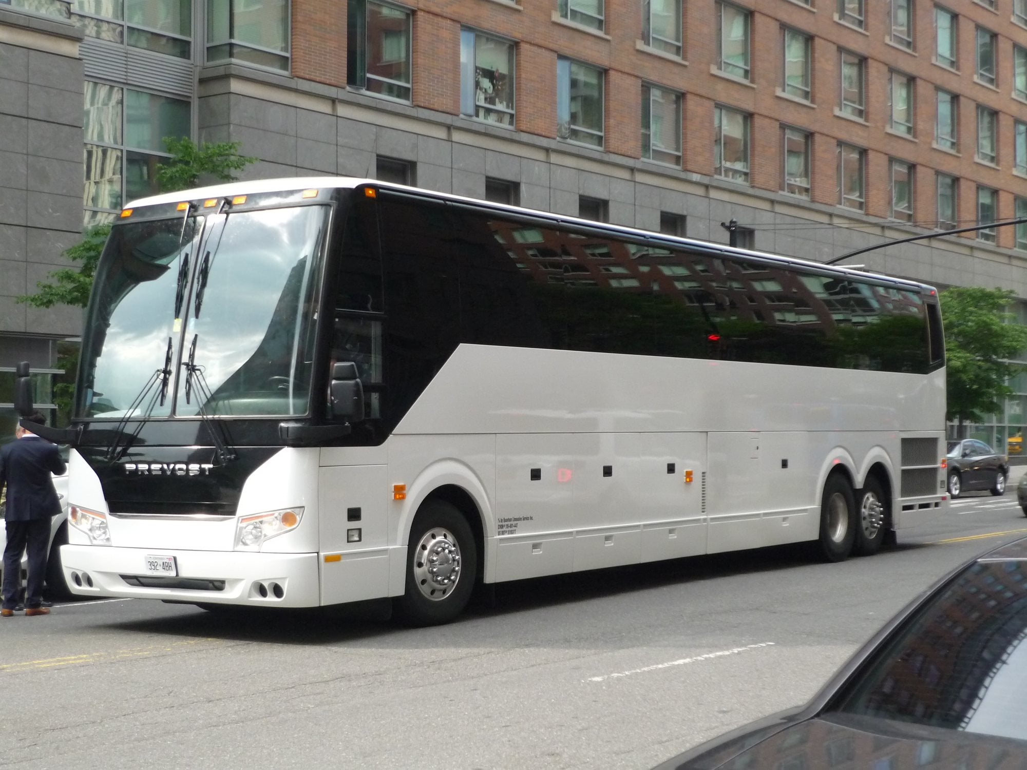 A white Prevost motorcoach parked on a city street.