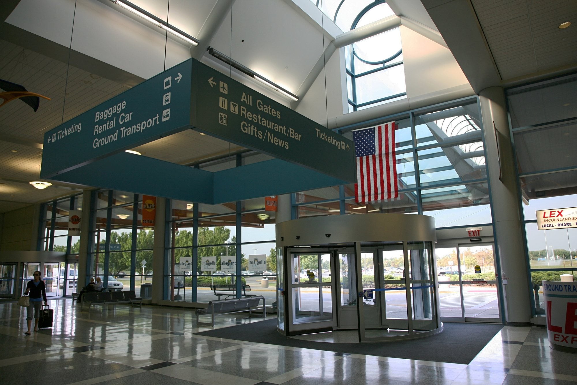 Overhead wayfinding signs for baggage, rental car and ground transport inside the Willard Airport terminal.