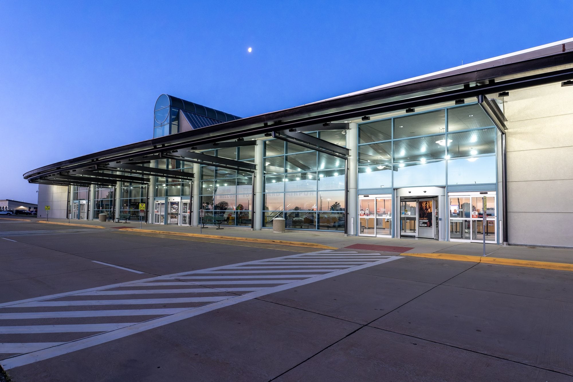 The lit glass terminal building at University of Illinois Willard Airport in Savoy at dusk with the departures entrance empty